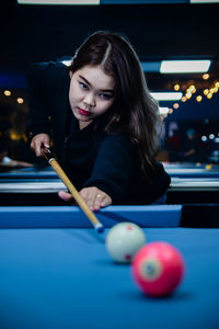 Portrait of young woman playing pool