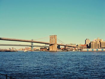 Suspension bridge over sea against clear sky