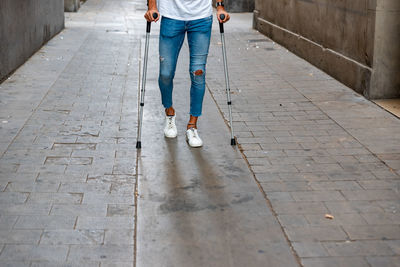 Unrecognizable young man with crutches visiting the city