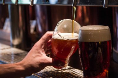 Close-up of person holding beer glass on table