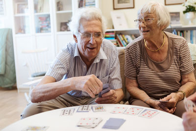 Senior couple playing cards at table in nursing home