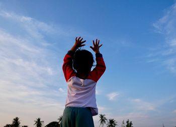 Low angle view of girl standing against sky