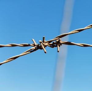 Low angle view of barbed wire against clear blue sky