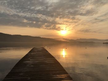 Pier over lake against sky during sunset