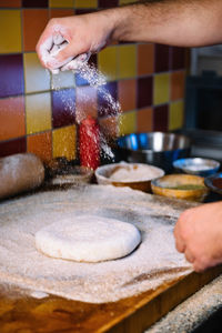 Close-up of man preparing dough in kitchen