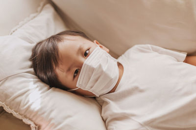 High angle view of cute boy resting on bed at home
