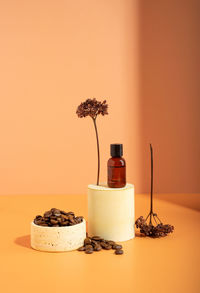 A brown coffee essential oil on a pedestal and coffee beans. wildflowers. still life, skin care