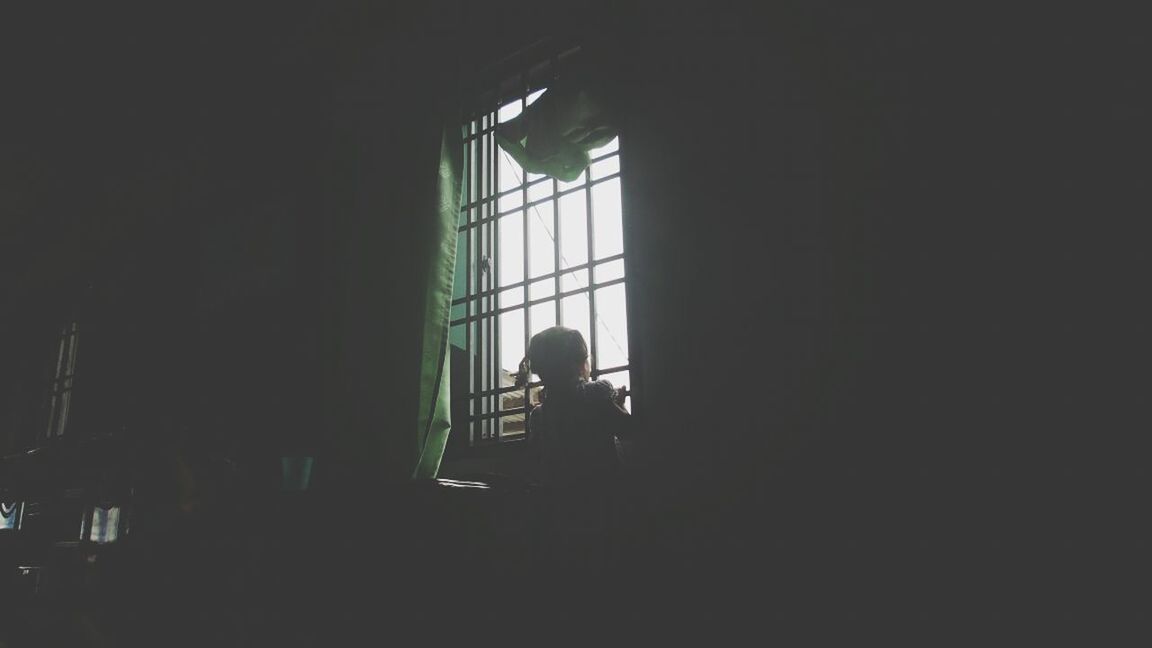 indoors, silhouette, window, lifestyles, men, leisure activity, dark, person, architecture, built structure, standing, rear view, sitting, full length, sunlight, looking through window, unrecognizable person