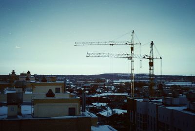 Construction site by buildings in city against clear sky