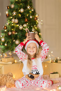 Portrait of cute girl decorating christmas tree at home