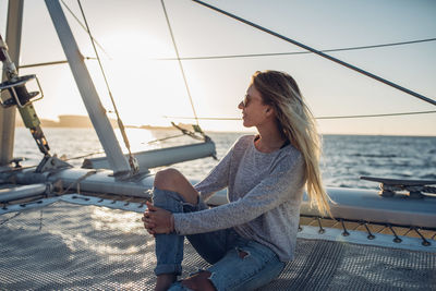 Woman sitting on boat in sea against sky