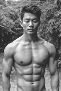 Portrait of shirtless man standing against trees