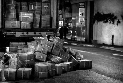 Street amidst buildings in city at night paper boxes in a pile in behind a truck 