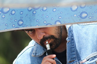 Portrait of man holding pen by umbrella