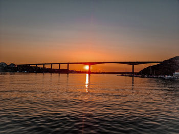 Bridge over sea against sky during sunset
