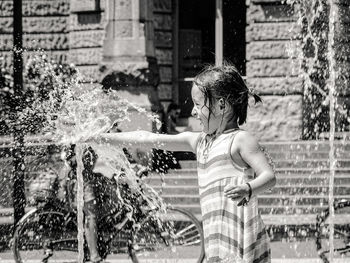 Full length of girl splashing water fountain