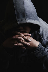 Close-up of woman in hood clothing against black background