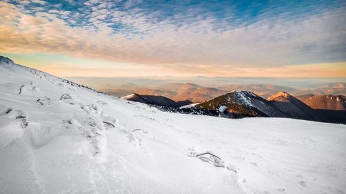 Scenic view of snow covered mountains against sky during sunset