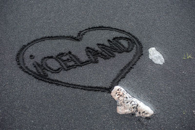 Iceland word handwritten on black beach sand inside a heart