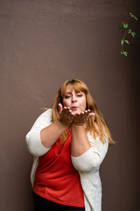 Portrait of young woman standing against wall