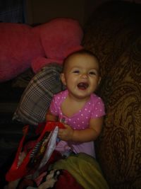 Portrait of cute baby girl sitting on bed at home