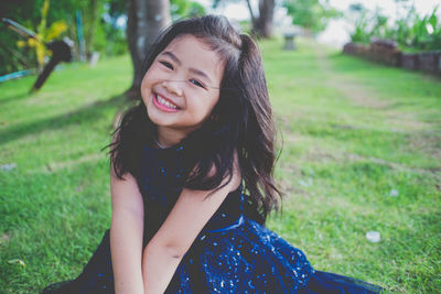 Portrait of smiling girl on grassy field at public park