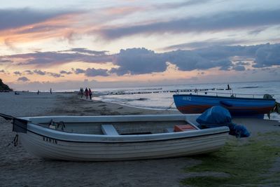 Boat moored on beach against sky during sunset