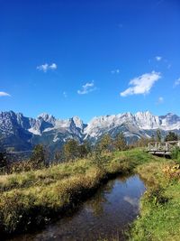 Scenic view of lake by mountains against blue sky