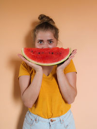 Portrait of man holding red fruit against gray background