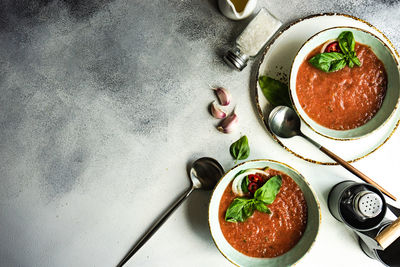 Traditional spanish tomato soup gazpacho derved in ceranic bowl with fresh basil leaves