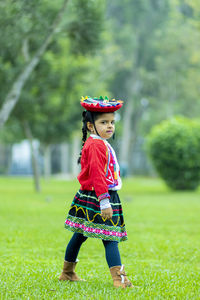 Full length of cute girl wearing hat standing on grass