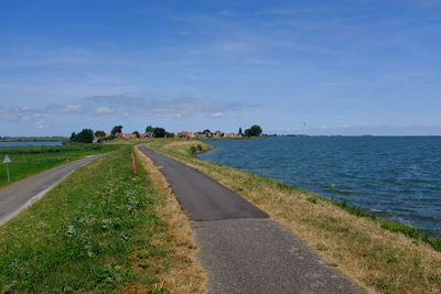 Empty road by sea against sky