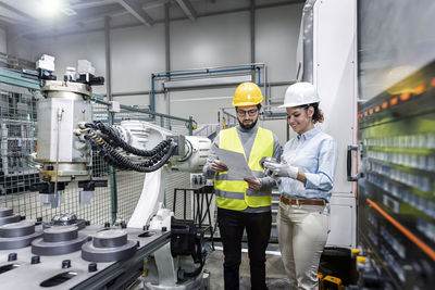 Business people standing with blueprint in factory