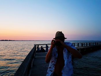 Man standing on beach against clear sky during sunset