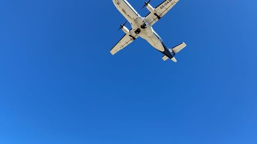 Low angle view of airplane against clear blue sky