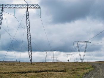 Electricity pylon on field against sky