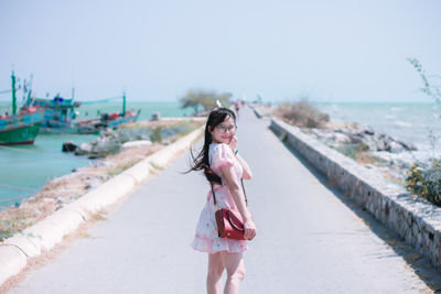 Portrait of woman standing on land by sea against sky