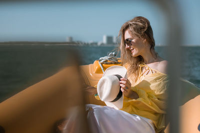 Young woman drinking glass while sitting outdoors