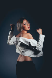 Rear view of seductive woman wearing jacket standing against black background