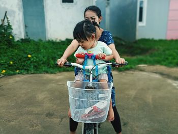 Girl sitting on bicycle with mother