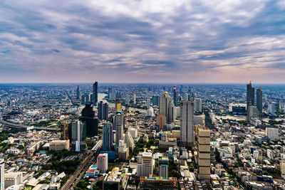 High angle view of city buildings against cloudy sky