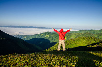 Man standing on field by mountain against sky