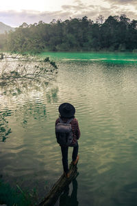 Rear view of man standing by lake against sky