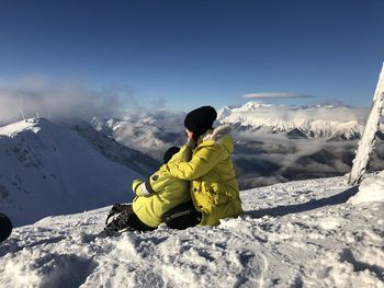 Rear view of people sitting on snow covered mountain