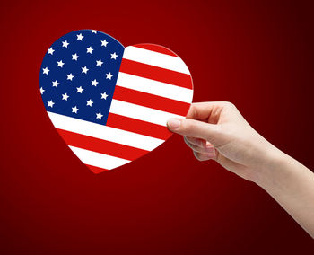 Close-up of hand holding flag against white background