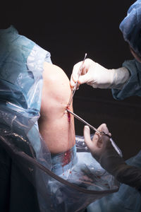 Midsection of surgeons doing knee surgery in hospital