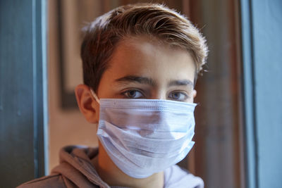 Close-up portrait of boy wearing mask at home