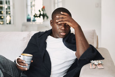 Close-up of depressed man holding coffee cup at home