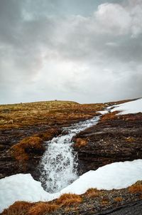 Scenic view of waterfall against sky during winter