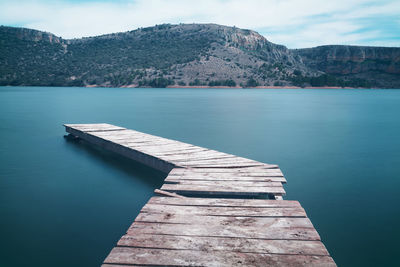 Broken pier on river against mountains